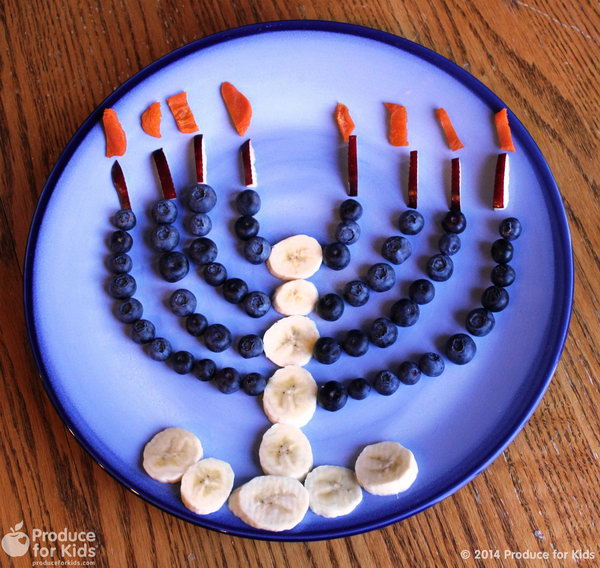 Celebrate Hanukkah with this fun menorah made using fresh fruits and vegetables. Use a little bit of yogurt to help the fruit stick to the plate. 