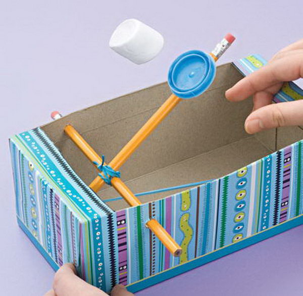 A Marshmallow Catapult for kids made from 2 pencils, a rubber band, a shoe box, and a milk cap. These would be fun and safe to create during force and motion lessons. 