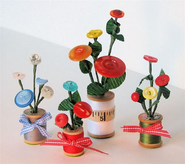 Button Flowers in Thread Spool Vases. They are decorated with bits of ribbon or vintage sewing supplies. 